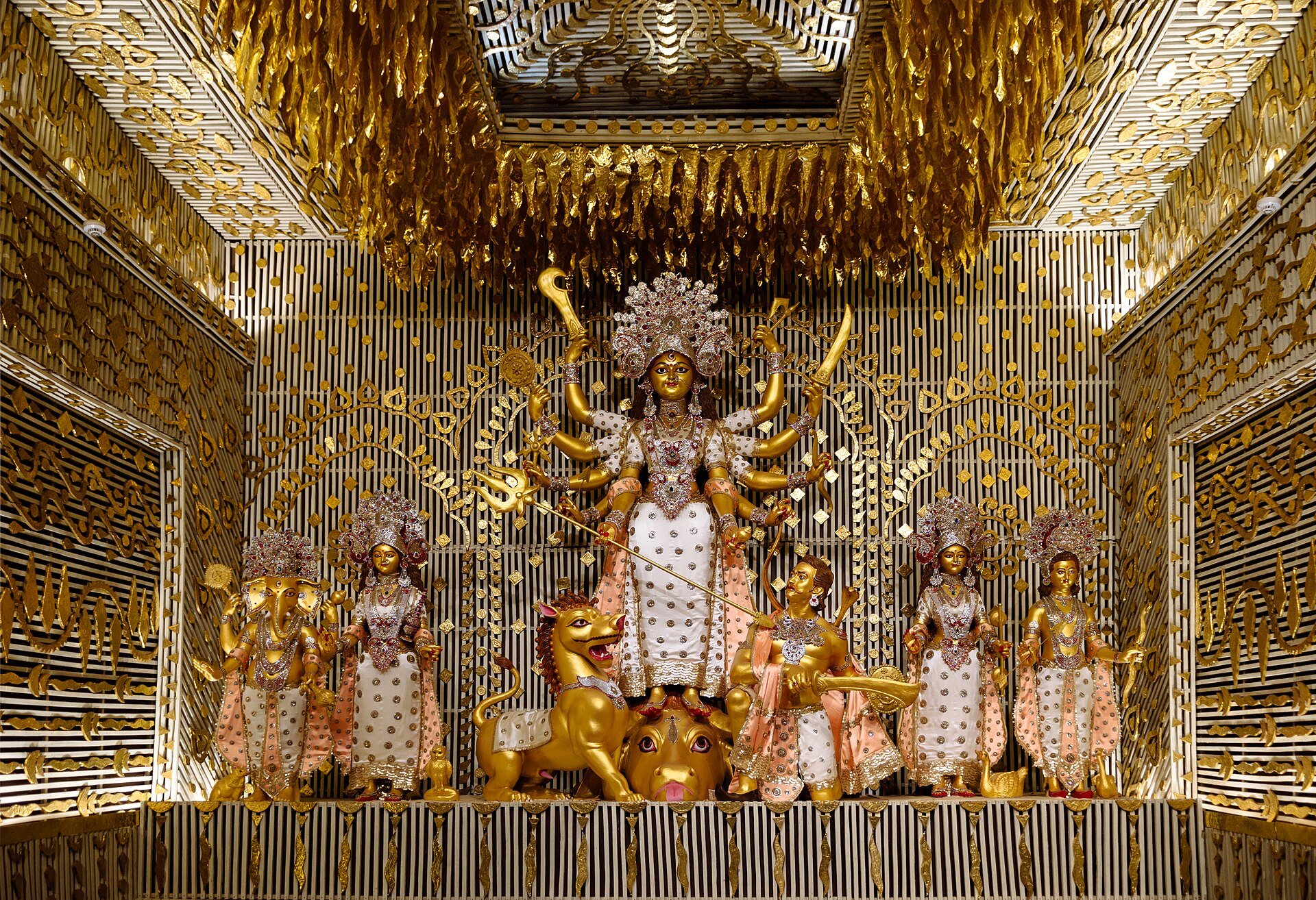 A Durga Puja pandal in Kolkata at night, the idol lit inside a temporary bamboo and cloth structure