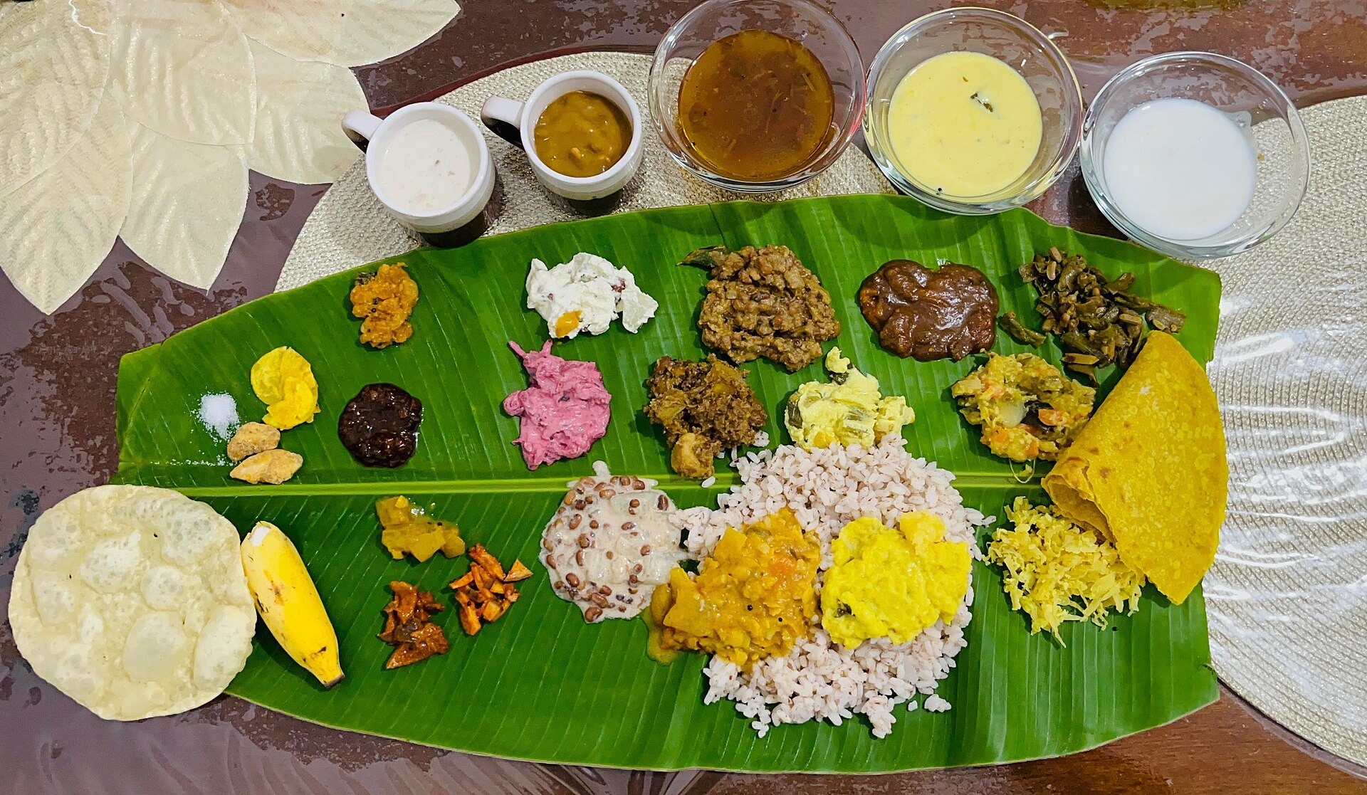 An Onam sadya laid out on a banana leaf, the dishes placed in their traditional order