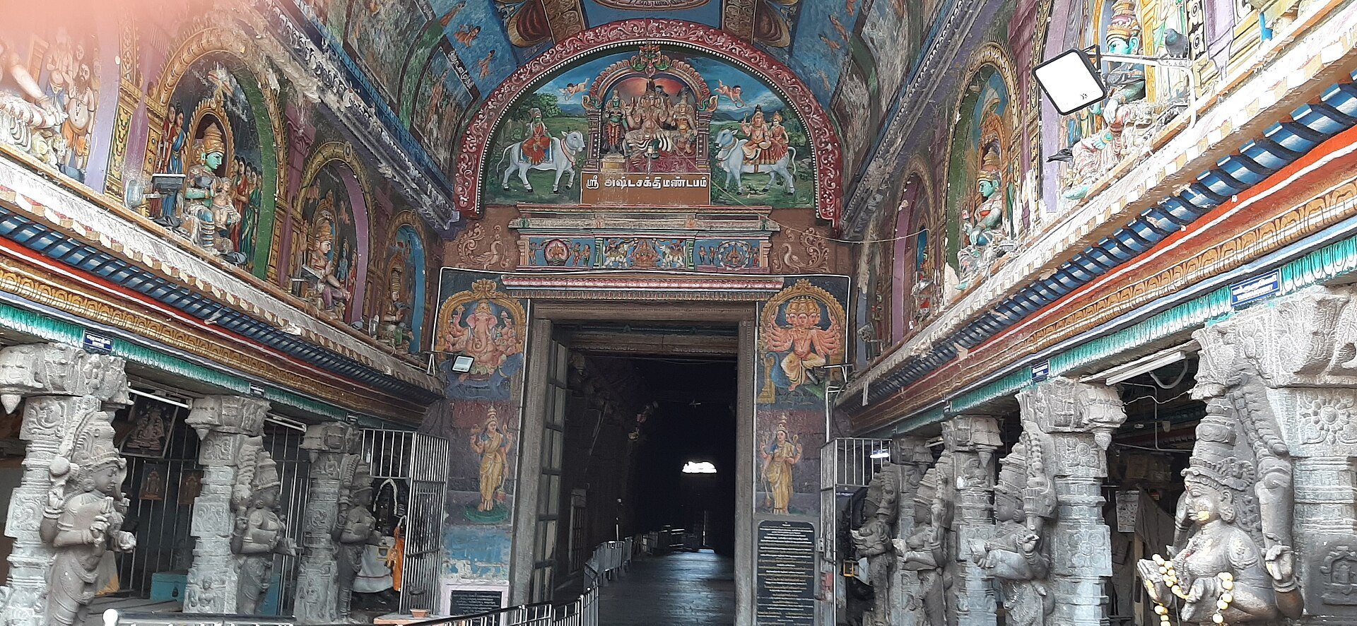 The painted ceiling and carved pillars of the Ashta Sakthi Mandapam at the Meenakshi temple in Madurai, the outer hall that is open to everyone, with the passage leading inward beyond it