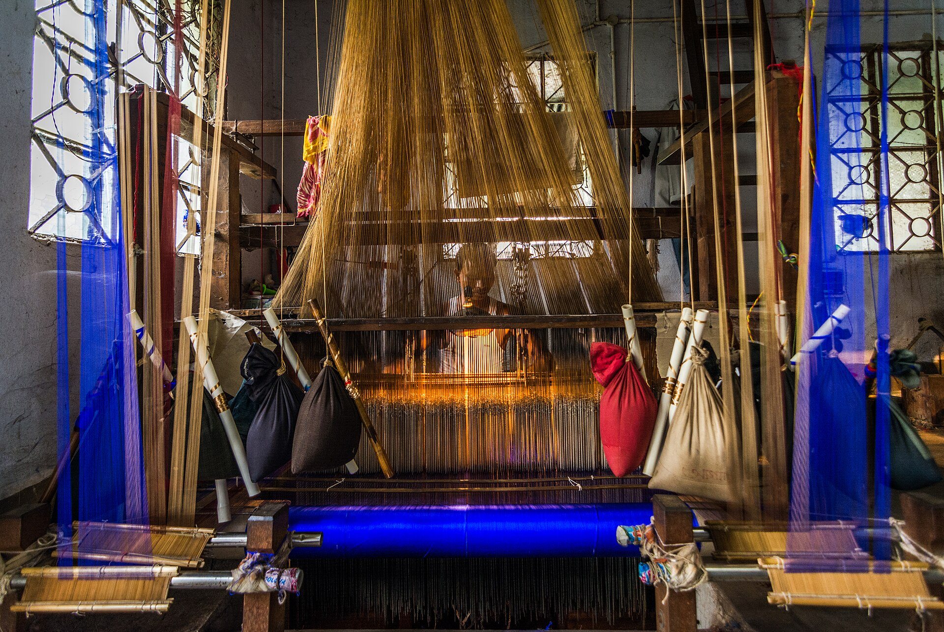 A handloom pit loom in a Bengal weaving village, warp threads stretched towards the shed