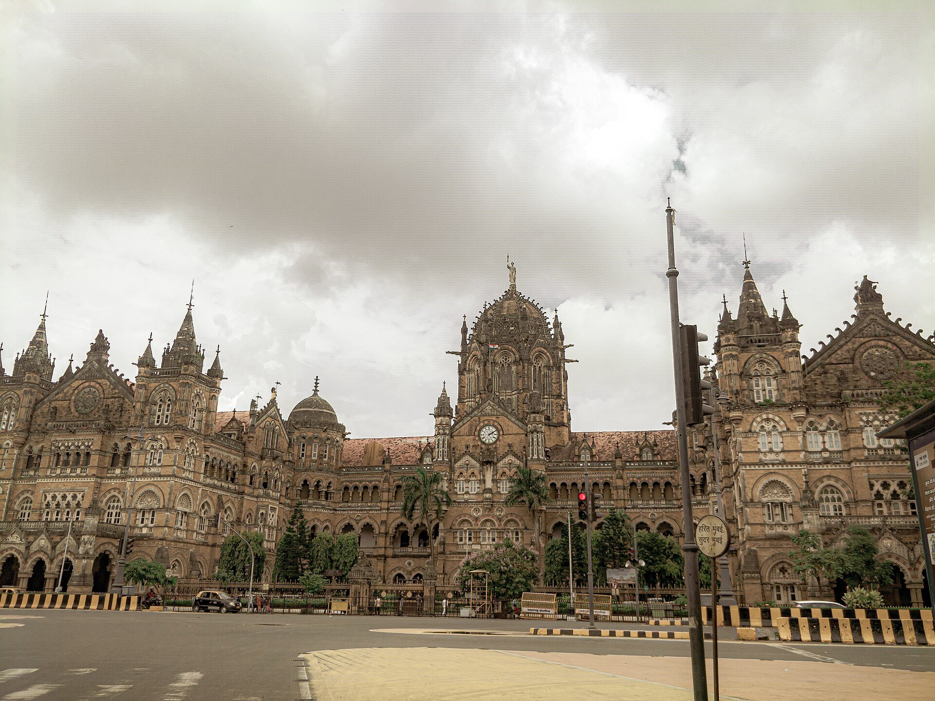 Chhatrapati Shivaji Maharaj Terminus in Mumbai under a heavy monsoon sky, the road in front of it empty